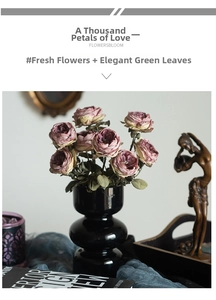 Artistic set of vintage faux roses in a glossy black ceramic vase on a classic table