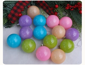 Gros plan de boules de Noël en plastique aux tons macaron sur une surface festive enneigée