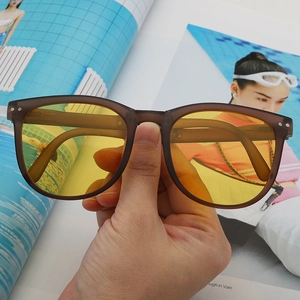 Detail shot of matte brown sunglasses with yellow transparent lenses and metallic hinge dots