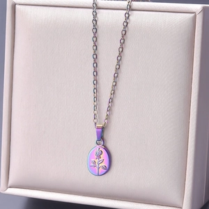 Detail of a thin chain necklace with a colorful rainbow rose relief pendant on a beige box