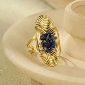 Detail of vintage gold adjustable ring with oval base and blue stone inlay on a ceramic dish