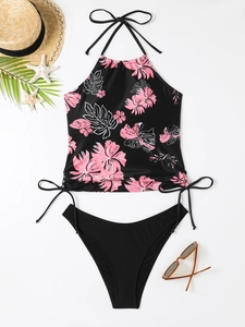 Flat lay of a floral halter bikini top with black bottoms and beach accessories