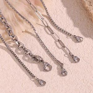 Flat lay of diverse stainless steel box and link anklets on a natural beach shell background