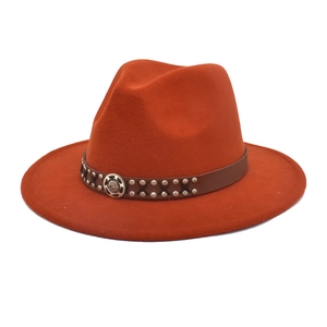 Detail of rust red wool fedora hat with brown leather band and metallic rivets