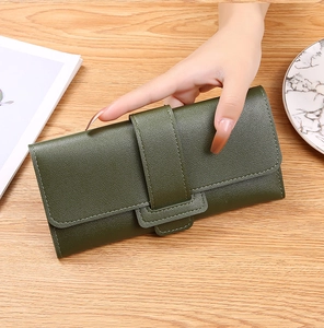 Close-up of a long dark green leather wallet held by hand on a wooden desk background