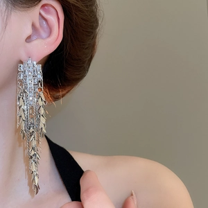 Detailed view of elegant silver tassel earrings with crystal leaf motifs on model