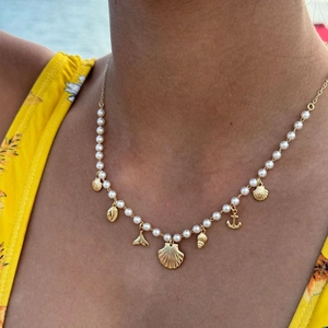 Summer pearl necklace with golden shell, fishtail, and anchor charms on model
