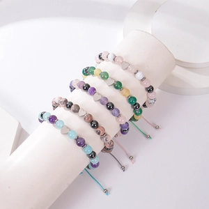 Detailed view of woven bracelets with natural stones and heart-shaped metal charms