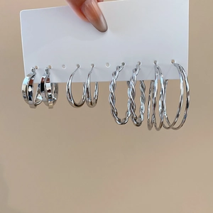 Detailed set of four silver twisted hoop earrings on display card with metallic luster
