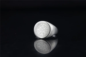 Macro detail of silver compass signet ring with brushed metal texture and reflection