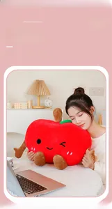 Detailed view of the soft red apple plush toy held by a model in a cozy home setting