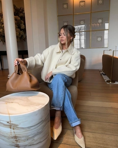 Detail of cream white wool jacket paired with brown leather tote and denim jeans
