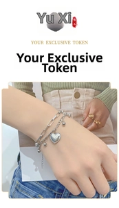 Double-layered silver bracelet featuring heart pendant and bead detail on a model's wrist