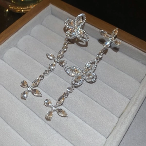 Detailed view of silver butterfly tassel earrings with sparkling cubic zirconia on velvet