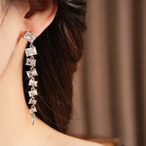 Detail of silver long tassel earrings with sparkling square cut cubic zirconia on a model