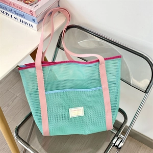 Close-up of mint green mesh beach tote bag with pink canvas straps and blue front pocket