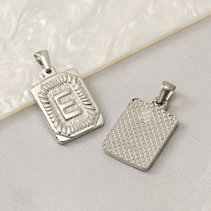 Vue recto-verso du pendentif rectangulaire en acier titane 18K avec la lettre E