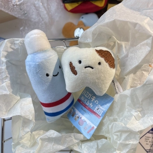 Detail showing plush toothpaste and tooth charms with ball chains in a metal basket