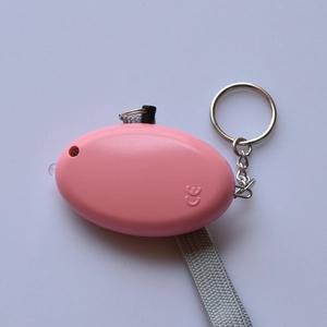 Pink egg-shaped personal safety alarm with LED light and keychain on textured background
