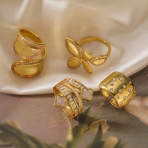 Elegant 18K gold-plated flower and geometric open rings set displayed on silk fabric