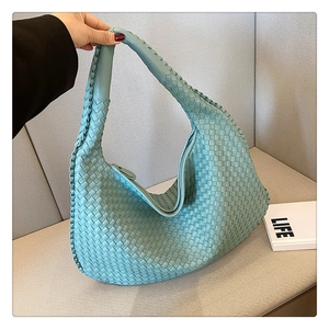 Detailed view of the woven texture and soft green leather on this hobo shoulder bag