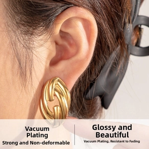 Close-up of chunky gold intertwined hoop earrings with polished finish on model