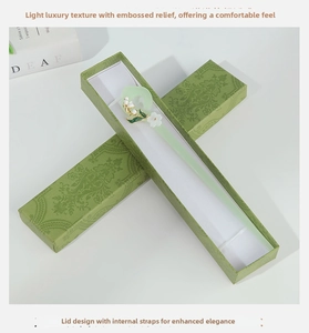 Detail view of a vintage green hair pin with white floral accents in a matching gift box