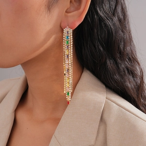 Detail of colorful tassel earrings with square rhinestones on a gold setting worn by model