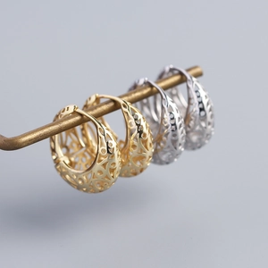 Detailed view of hollow patterned C-shape hoop earrings in gold and silver finishes