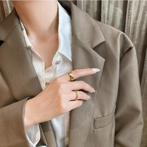 Minimalist 18K gold plated titanium steel stackable rings worn on a brown blazer fabric
