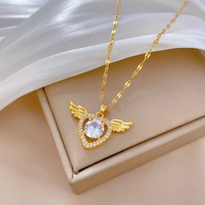 Gold winged heart necklace with clear zircon pendant on beige jewelry box display