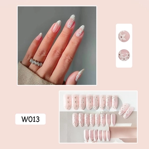 Detailed view of pink French press-on nails with white flower patterns on model's hands