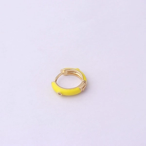 Close-up of yellow enamel gold earring with a small sparkling diamond on purple background