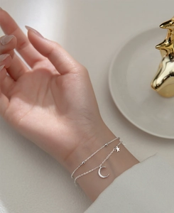 Dettaglio del bracciale a doppio strato in argento S925 con ciondoli stella e luna al polso