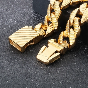 Macro detail of golden Cuban link bracelet showing diagonal textured engraving and clasp