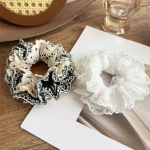Detailed close-up of handmade multi-layered lace scrunchies in black and white colors