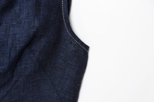Makrodetail der dunkelblauen Denim-Weste mit Fokus auf Nähte und hochwertige Baumwolltextur