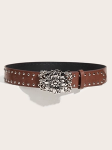 Close-up of brown leather punk belt with silver floral buckle and metallic rivet studs