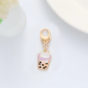 Close-up of a pink milk tea keychain with a cute white cat and a gold heart clasp