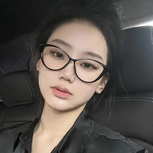 Close-up of black cat-eye glasses frame worn by a model in a car interior setting