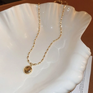 Close-up of vintage golden earring with brown tiger eye stone on white shell tray