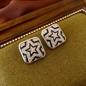 Detailed view of silver square stud earrings with black star and sparkling diamonds