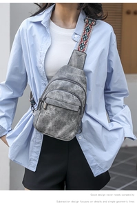 Close-up of grey leather crossbody bag with colorful ethnic style woven shoulder strap
