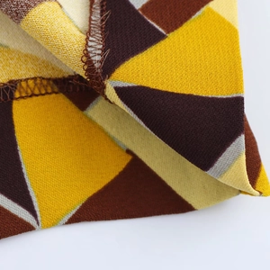 Dettaglio del tessuto con stampa geometrica gialla e marrone con cucitura overlock