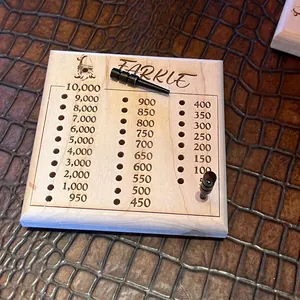 Macro detail of wooden Farkle scoring board with engraved numbers and metal metal pegs