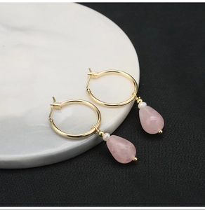 Detail of pink crystal drop earrings with small pearls and gold finish on ceramic edge