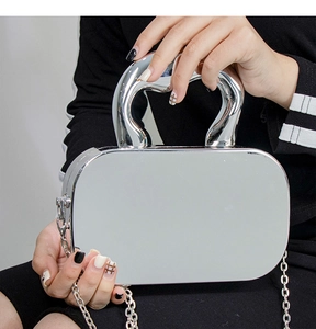 Detail of silver acrylic mirror box bag with rigid curved handle and metal chain strap