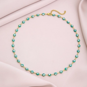 Close-up of golden stainless steel necklace with green enamel evil eye beads detail