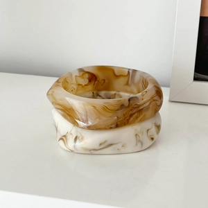 Detailed view of amber and cream marble resin bangles stacked on a white surface