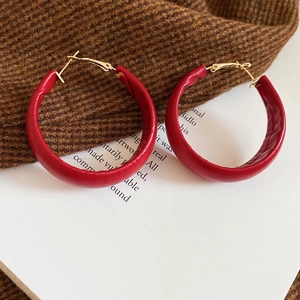Detail of red leather-wrapped hoop earrings with gold needles on vintage fabric